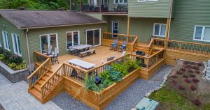 A large cedar deck on multiple levels with a green home