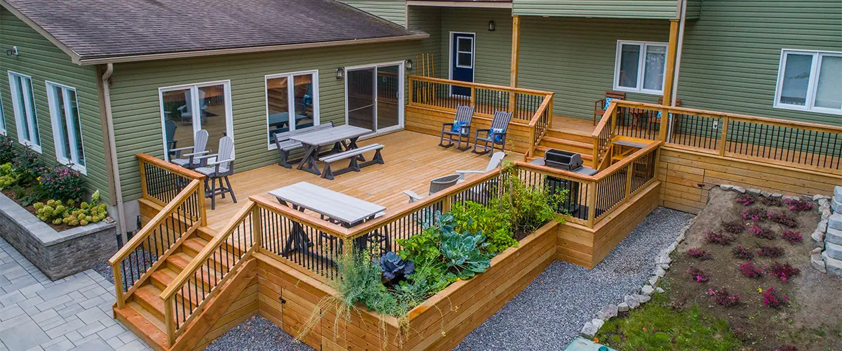 A large cedar deck building on multiple levels with a green home