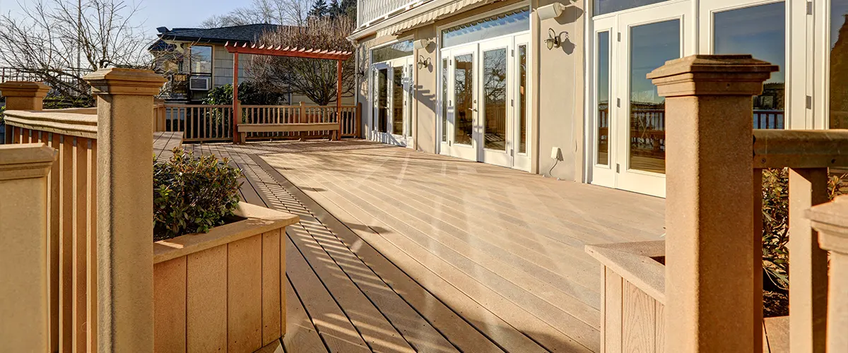 Composite decking with railing attached to a home with large window doors
